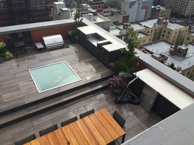 Resident roof deck with walkable skylight, outdoor kitchen, parapet, pavers.